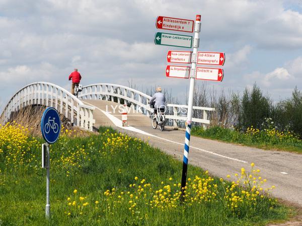 Stel op fiets bij brug in polderlandschap [00993291]