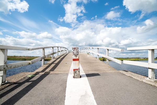 Houten voetgangers en fietsersbrug over het riviertje de Groote of Achterwaterschap in de polders bij Streefkerk in de Molenwaard