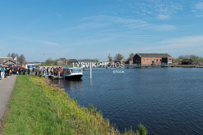 Aziatische toeristen stappen in rondvaartboot bij Kinderdijk [003279]