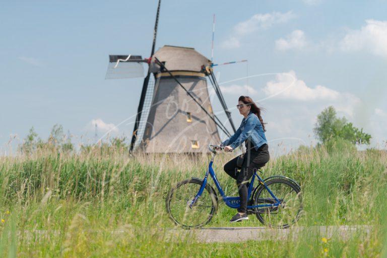 Vrouw fietst bij de molens in de Kinderdijk D8E0032929