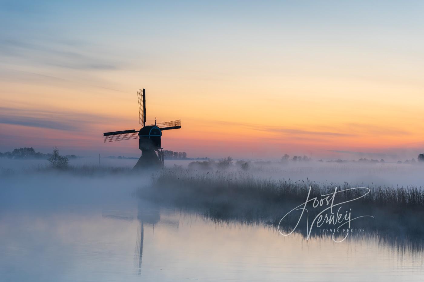 Broekmolen in mist bij zonsopkomst