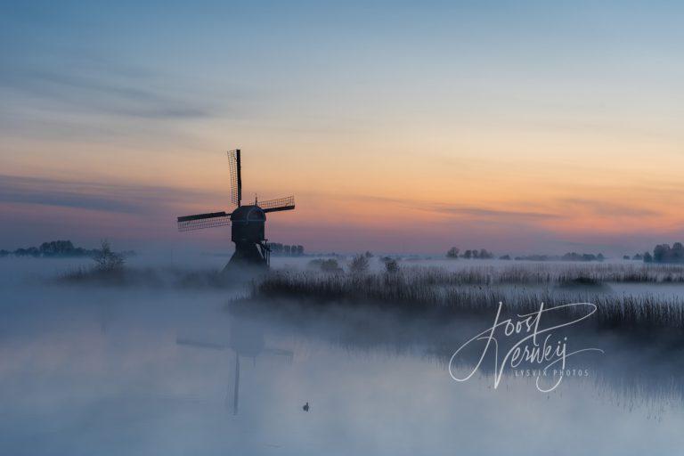 Broekmolen in mist bij zonsopkomst