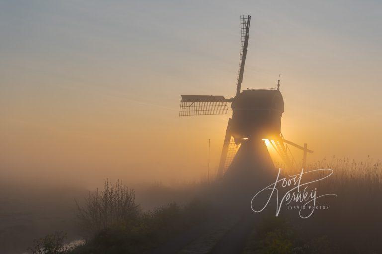 Broekmolen in mist bij zonsopkomst